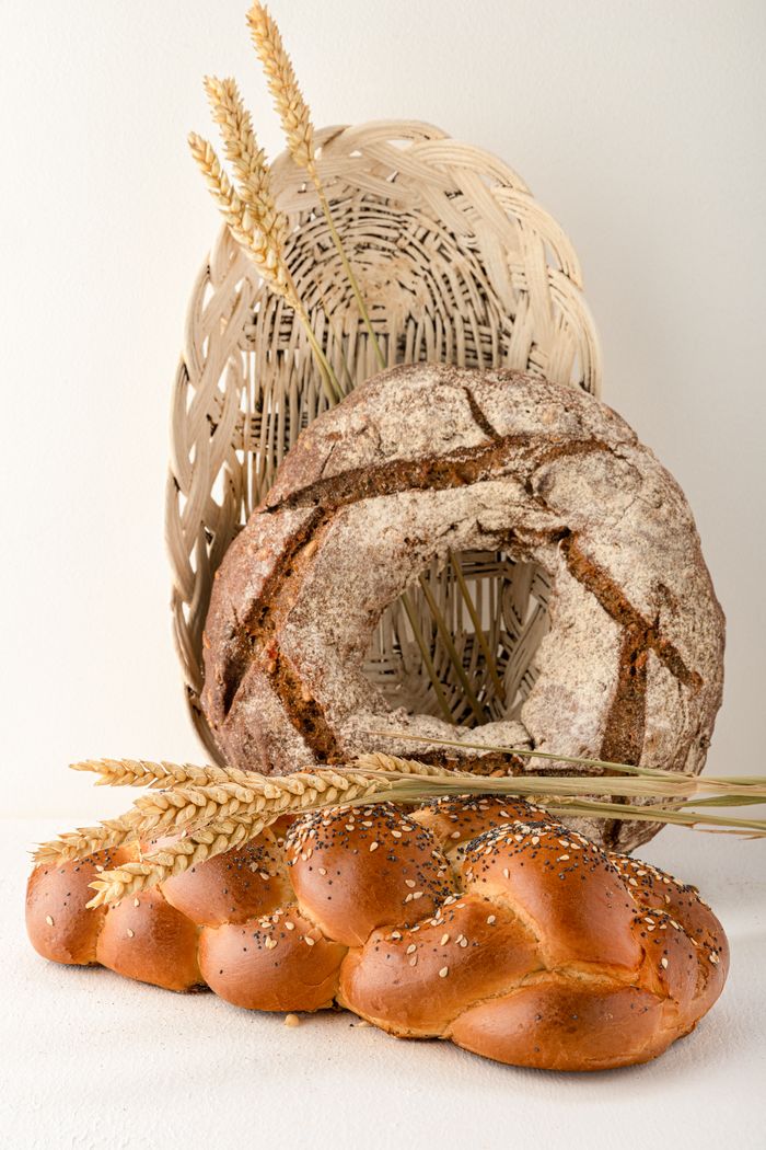 Close-up view of artisan breads with wheat in a basket for a rustic food presentation.